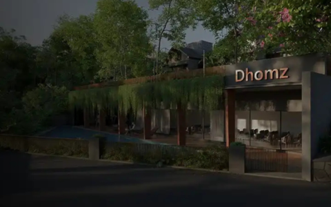 Entrance view of a premium gated villa community by Dhomz, featuring contemporary architecture, landscaped greenery, elegant lighting, and a welcoming clubhouse.