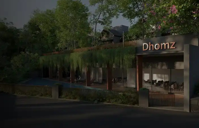 Entrance view of a premium gated villa community by Dhomz, featuring contemporary architecture, landscaped greenery, elegant lighting, and a welcoming clubhouse.